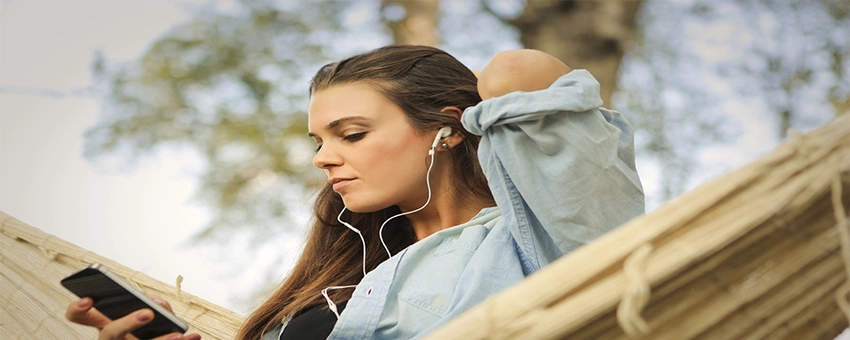 A woman listening to video on her phone with headphones